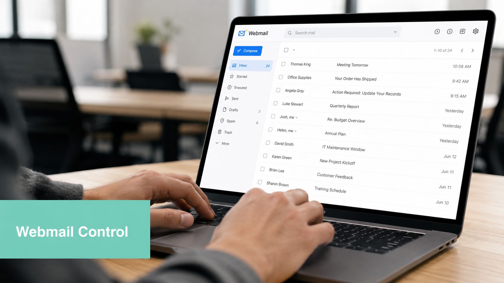A person typing on a laptop displaying a webmail inbox interface in a modern office setting.