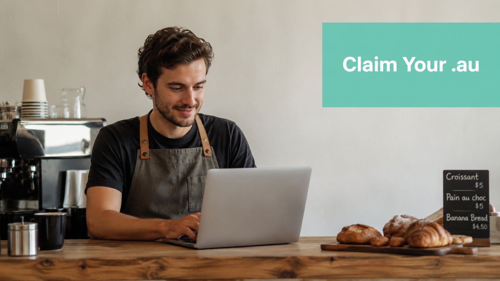 Domain Registration Requirements: A 2026 Guide For Australian Businesses 3 A smiling barista wearing an apron works on a laptop behind a cafe counter with fresh pastries.