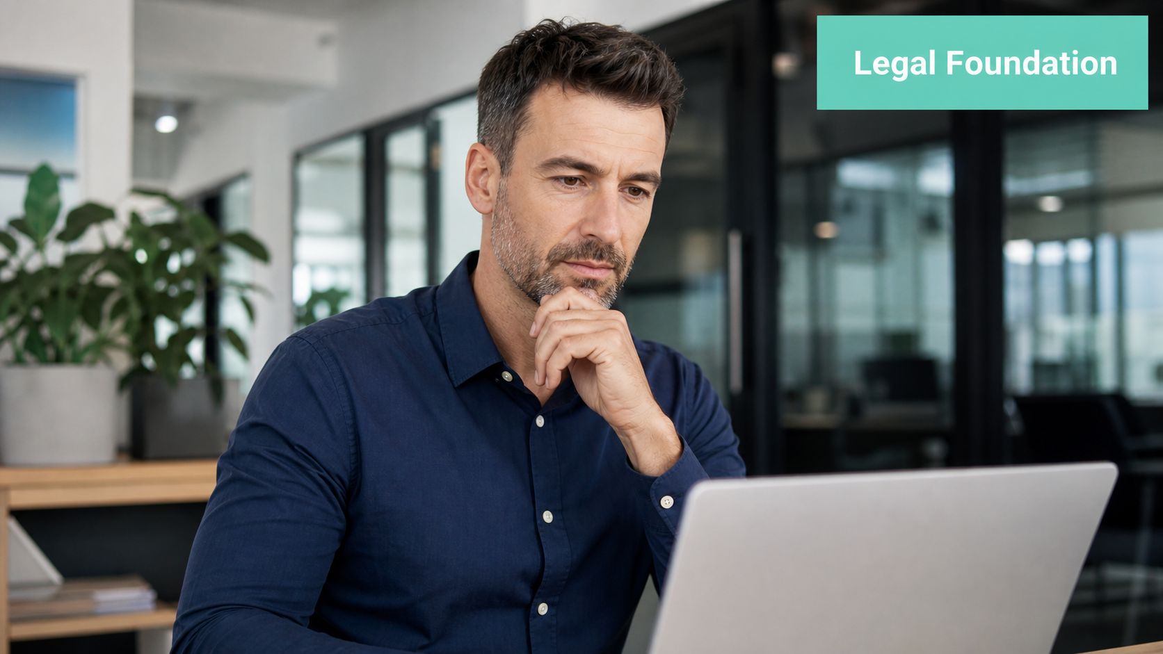 Website Legal Requirements Australia: Your 2026 Guide 2 A professional man looking thoughtfully at his laptop in a modern office with the text legal foundation.
